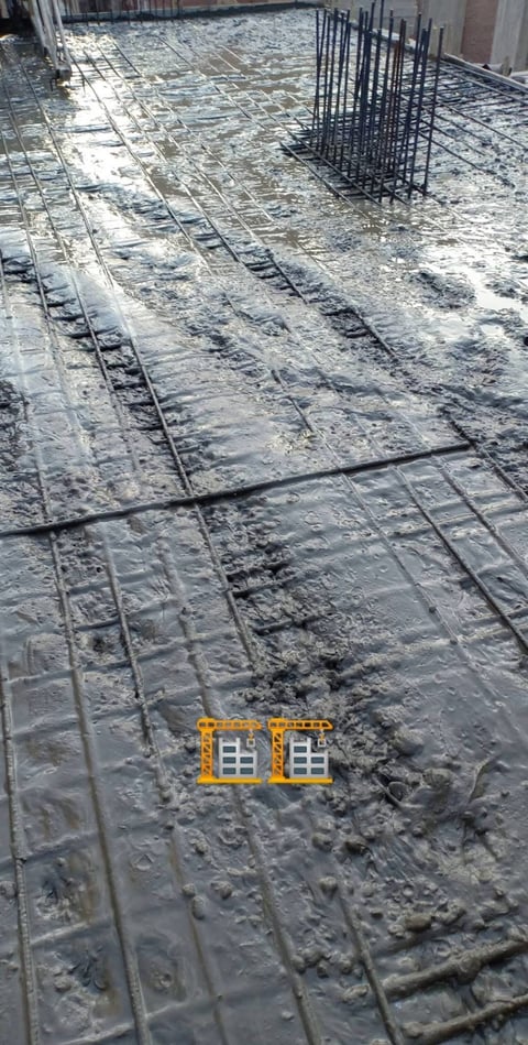 Construction site with concrete foundation, rebar grid, and vertical steel reinforcement bars, partially covered with plastic sheeting