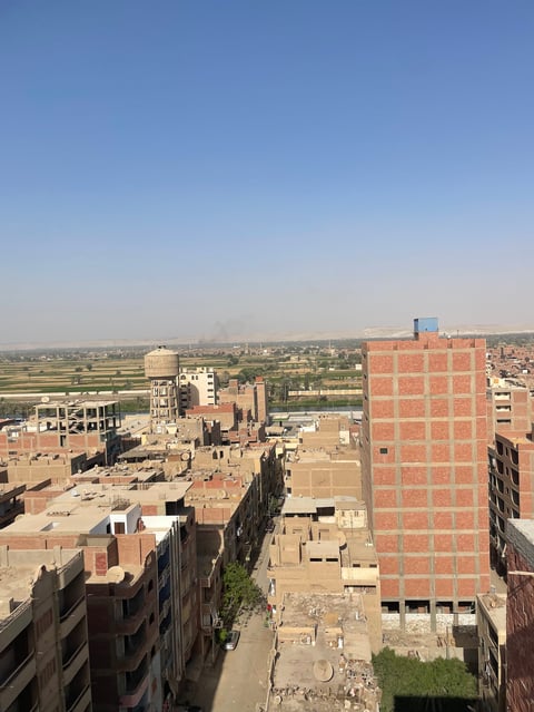 Elevated view of a dense urban residential area with brick apartment buildings and expansive countryside landscape in the distance